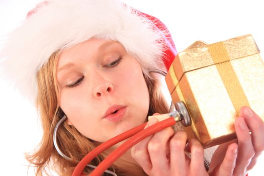 miss santa is sounding a golden gift box with a stetoscope to check out the gift box content - surprised curious look