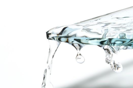 Piece of glass with flowing water on white background