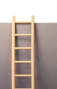 Wooden ladder standing near gray paper wall with copy spase