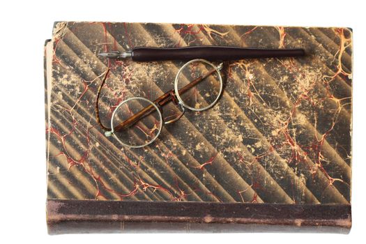 Vintage spectacles and fountain pen lying on old book. Isolated with clipping path