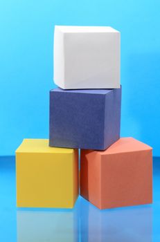 Four various colored paper cubes isolated on blue background