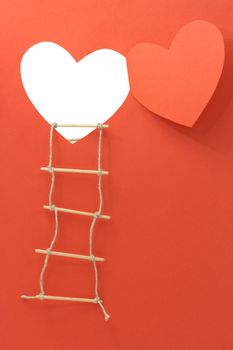 Rope ladder hanging on the wall with open window like a heart made from red paper. With clipping path for your images