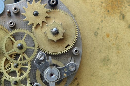 Closeup of old metal clock mechanism on yellow brass background