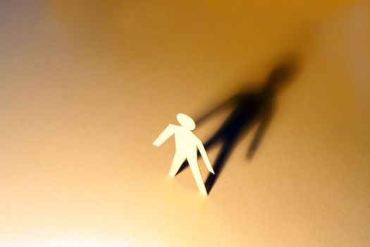 Paper man standing against his shadow on colored background