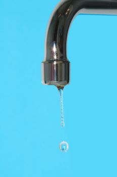 Water flowing from stopcock closeup on blue background