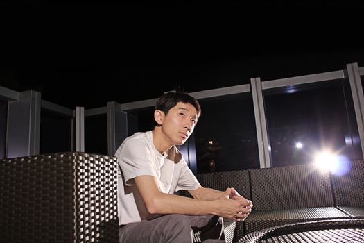 Man sit on a bench while relaxing at a pub. 