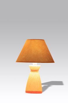 Nice luminous table lamp with yellow shade isolated on gradient background with clipping path
