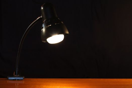 Nice luminous modern black table lamp standing on wooden table