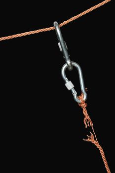 Two connected carabiners hanging on the disrupt rope. Isolated on black with clipping path