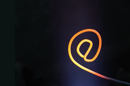 Scorching e-mail symbol made from wire on dark background with copy space