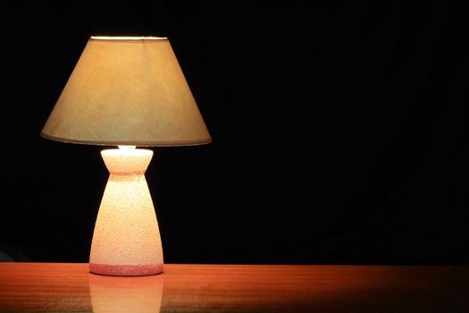 Nice luminous table lamp with yellow shade standing on wooden table