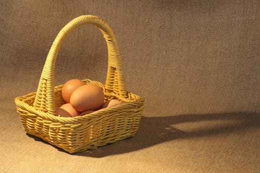 Yellow basket full of eggs on canvas background with copy space