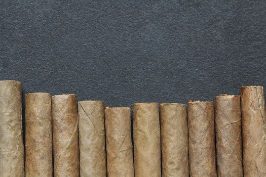 Closeup of cigar's row on dark metal background