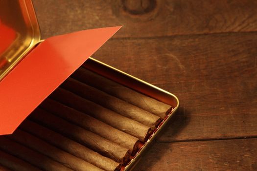Open metal box of cigarillos isolated on wooden background
