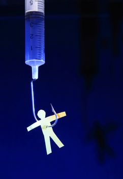 Yellow paper man hanging on syringe with fish hook on dark background