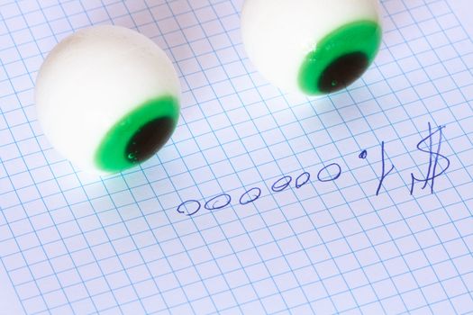 Two toy eyes lying on paper with inscription One million dollars