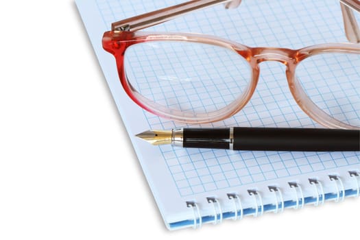 Closeup of spectacles and fountain pen lying on spiral notebook. Isolated with clipping path