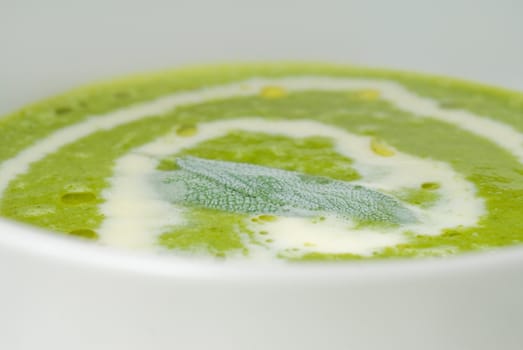 fresh spinach soup on a white bowl with sage and cream on top