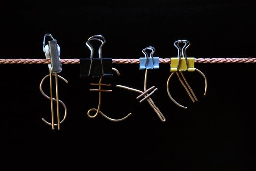 Abstract dark background with world currency signs made from brass wire hanging on the rope