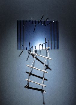 Rope ladder hanging on the prison wall with sawed metal bars