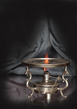 Vintage table spirit stove isolated on dark background with reverberation
