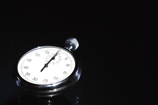 Closeup of old stopwatch isolated on black background with copy space