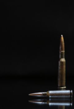Two high power rifle cartridges on a dark background with copy space