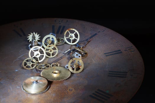 Old watch details lying on vintage rusty clock dial on dark background