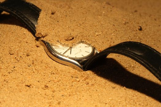 Closeup of hand watch lying on sand background