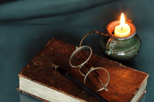 Vintage still life with candle and old things: book, spectacles,pen