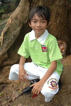 photograph of little asian boy sit down in park