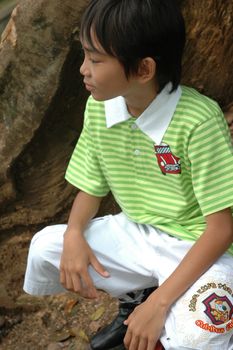 photograph of little asian boy sit down in park