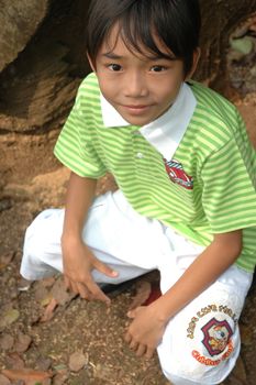 photograph of little asian boy sit down in park