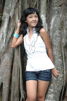 little asian girl stand up beside the tree in park