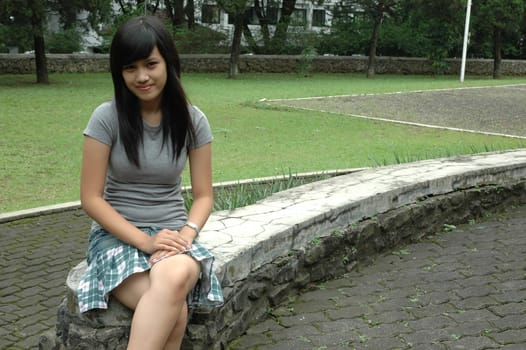 young asian lady sit down in park