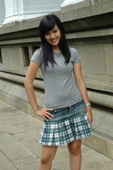 young asian lady stand up beside solid rock wall