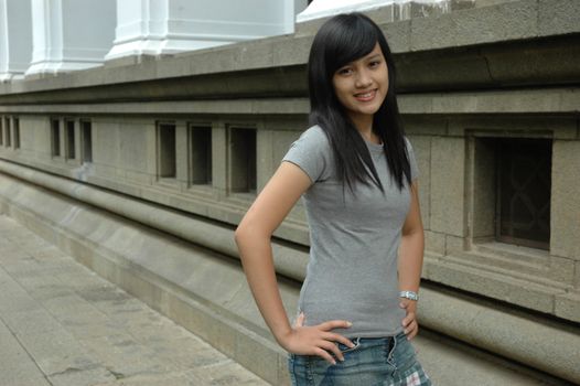 young asian lady stand up beside solid rock wall