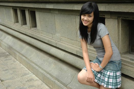 young asian lady stand up beside solid rock wall