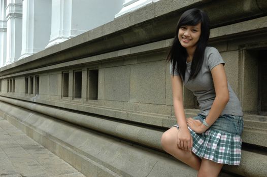 young asian lady stand up beside solid rock wall