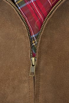 close-up of unzipped brass zipper of chamois leather jacket showing a red scarf
