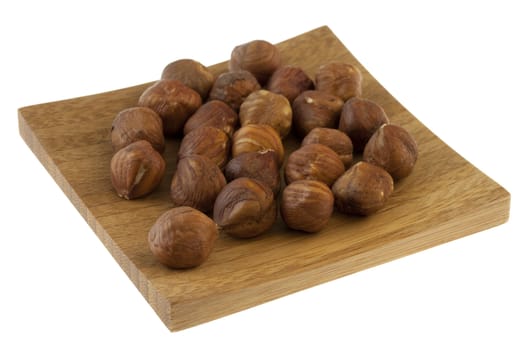 filberts (hazelnuts) on a small wooden square tray, isolated on white