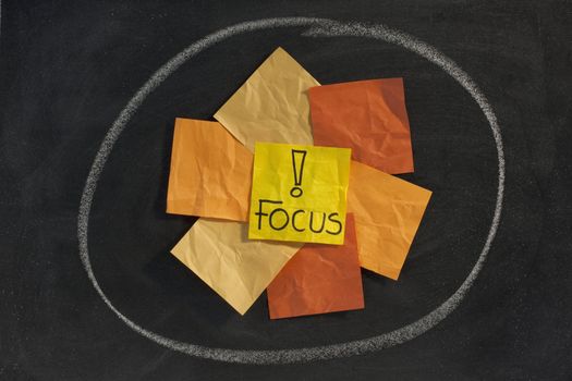 focus word with exclamation mark - yellow, orange, brown sticky notes  posted on blackboard 