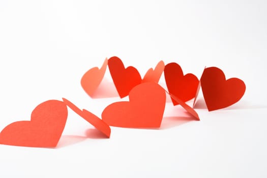 Abstract composition with red paper hearts on white background