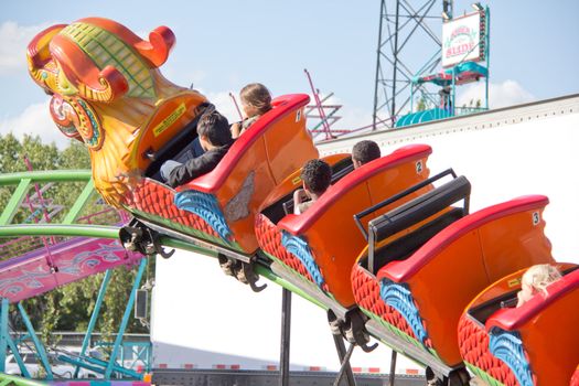 Kids riding the dragon roller coaster as it zooms on its track