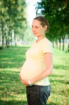 Beautiful pregnant woman relaxing on the grass in the park