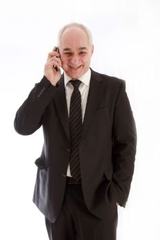 Laughing, older businessman in a suit and has telephoned one hand casually in his pocket