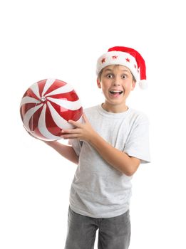 An excited ecstatic boy holding a big Christmas bauble ball decoration.  Red and white with sparkling glitter and a silver thread