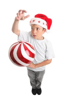 A boy standing is spinning or hanging a large Christmas bauble.    Bauble shows some motion.