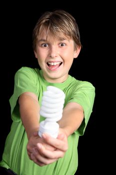 A boy wearing a green t-shirt holding out a green energy efficient light bulb