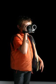 A child standing in a room or studio using a handheld digital video camera